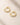 Pair of ENVYONE 18K Gold Plated hoop earrings with sparkling zircon stones, arranged side by side on a textured beige surface.