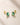 18K Gold Plated stud earrings with Emerald Cut Green Zircon in a four prong setting, displayed on a light beige stone surface.