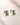ENVYONE emerald green gemstone stud earrings with rectangular stones set in polished 18K Gold Plated settings, styled on a neutral stone surface.
