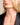 Closeup of a woman wearing an ENVYONE 18K Gold Plated circular pendant necklace with a dark green cubic zirconia stone and black blazer.