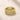 A stack of three ENVYONE 18K Gold Plated eternity rings featuring clear pavé and round-cut zircon stones on a textured beige stone surface.