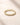 Closeup product photo of an ENVYONE 18K Gold-Plated ring with brilliant white zircon stones on textured beige stone.