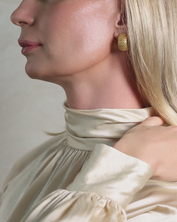 Video of model wearing ENVYONE 18K Gold Plated textured hoop earrings with an ivory silk top