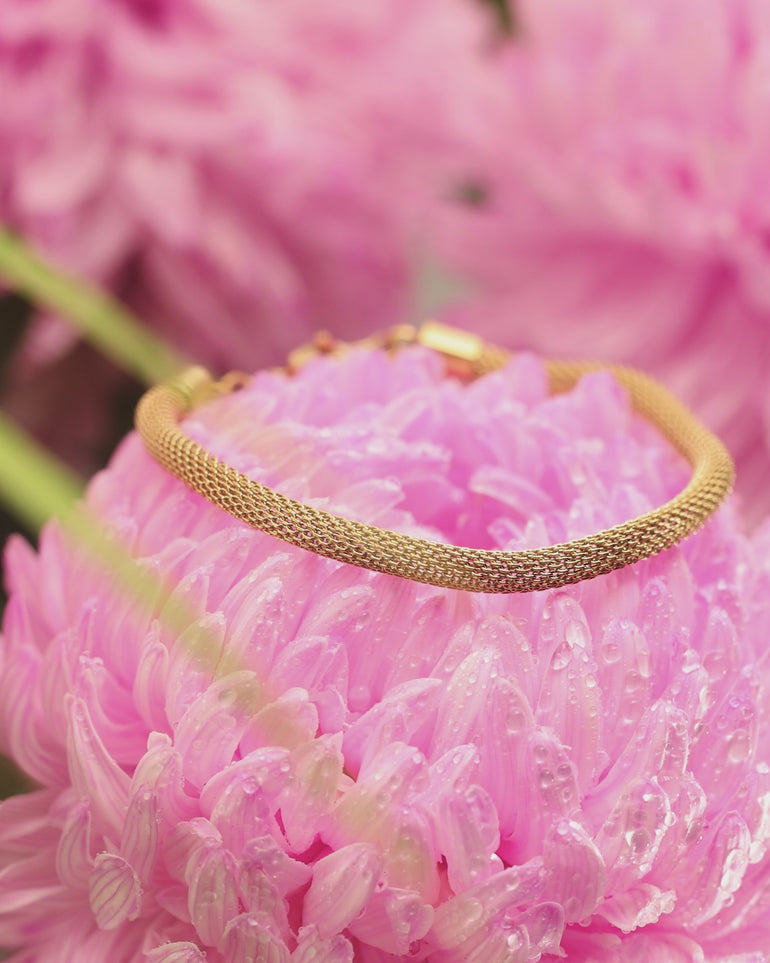 Macro video of ENVYONE 18K Gold-Plated mesh bracelet resting on a vibrant pink flower.