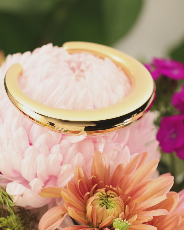 Close-up product video of ENVYONE 18K Gold-Plated stainless steel cuff filmed against a colourful floral background.