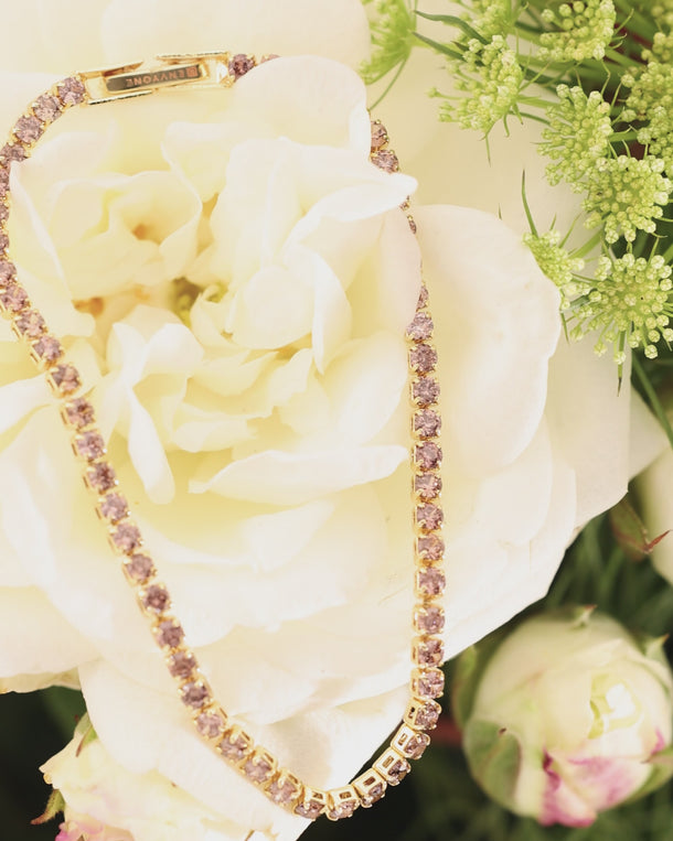 Video of an ENVYONE 18K Gold-Plated pink zircon tennis bracelet styled around a white flower.