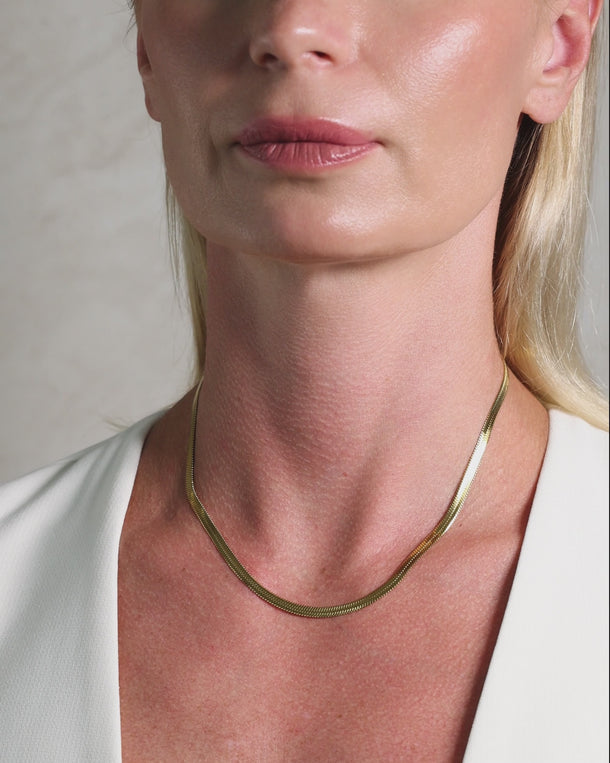 Closeup video featuring an ENVYONE 18K Gold-Plated Premium Stainless Steel herringbone chain necklace with a smooth polished finish worn by a woman.