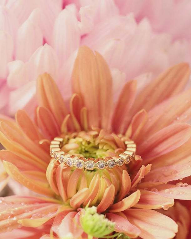 Closeup video of an ENVYONE 18K Gold Plated zircon eternity ring styled on an orange flower.