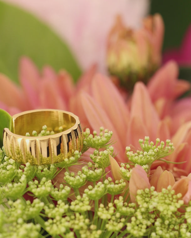 Closeup video of an ENVYONE 18K Gold Plated adjustable statement ring styled among vibrant pink flowers.