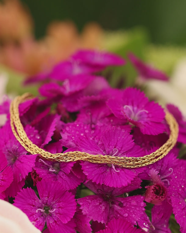 Product video of an ENVYONE 18K Gold-Plated multi-strand bracelet styled over vibrant pink flowers.