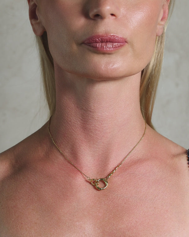 Video of a woman wearing an ENVYONE 18K Gold Plated stainless steel necklace with an organic interlocking pendant design.