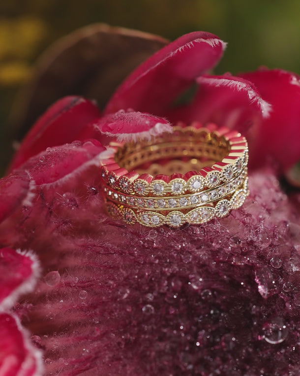 Video of ENVYONE 18K Gold Plated stacking rings with brilliant white zircon stones styled among vibrant pink flowers.