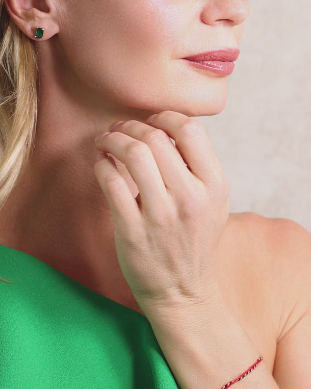 Video of a woman wearing ENVYONE 18K Gold Plated emerald gemstone stud earrings, showcasing their polished finish and refined statement design.